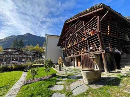 a large wooden building with mountains in the background at Stilish wooden chalet fully renovated near the lifts in Alagna Valsesia