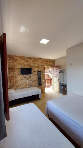 a bedroom with two beds and a brick wall at Chico Caranguejo da Baleia in Itapipoca