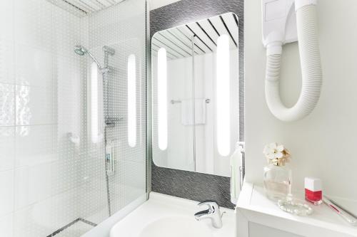 baño blanco con ducha y lavamanos en ACE Hôtel Travel Fabrègues - A9 Montpellier Sud, en Fabrègues