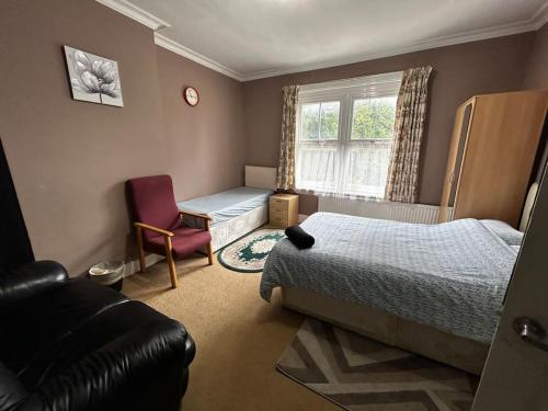a bedroom with a bed and a chair and a window at Amazing 6 bedroom house with free parking on site. in Norbury