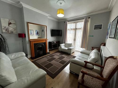 a living room with a couch and a fireplace at Amazing 6 bedroom house with free parking on site. in Norbury