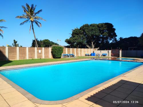 a blue swimming pool with a palm tree in the background at Stella Maris 55 in Amanzimtoti