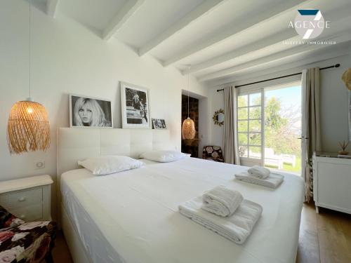 une chambre avec un grand lit blanc avec des serviettes dessus dans l'établissement La Romarine, à Grimaud