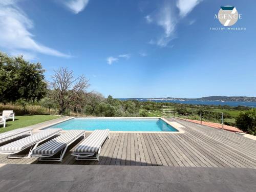 - une piscine avec 2 chaises longues sur une terrasse en bois dans l'établissement La Romarine, à Grimaud