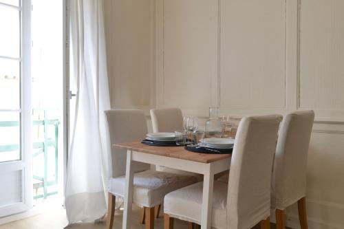 une table à manger avec des chaises blanches et une table avec des verres dans l'établissement Appartement à deux pas du port de pêche Les Sables - 4 personnes, à Les Sables-dʼOlonne