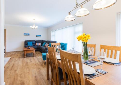 a dining room and living room with a table and chairs at Pared Isaf in Cardigan