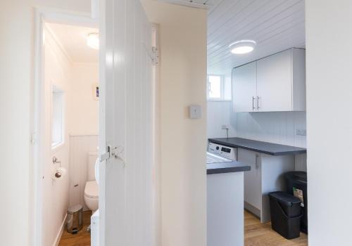 Una pequeña cocina con gabinetes blancos y un fregadero. en Pared Isaf, en Cardigan