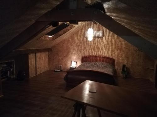 Cette chambre sombre comprend un lit et une table. dans l'établissement Le sas des familles, à Limoges
