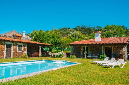 a villa with a swimming pool in front of a house at Just Like Home - Casa da Telheira in Caminha
