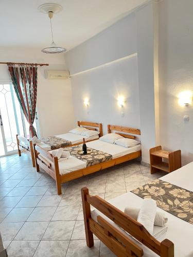 a room with three beds and benches in it at Hotel Katia in Paralia Katerinis