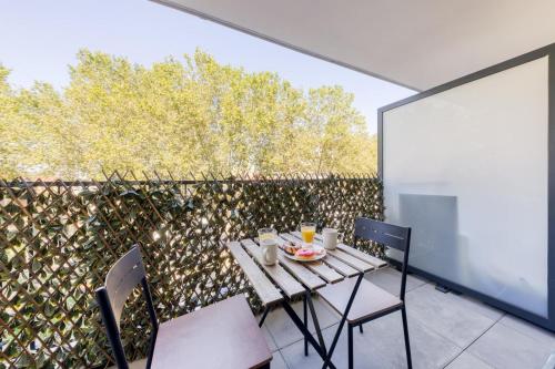 une table et des chaises sur une terrasse avec une clôture dans l'établissement Charmant appartement de haut standing proche du centre-ville, à Alfortville