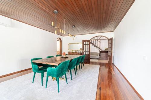 a dining room with a wooden table and green chairs at Portuguese Luxury Villa in Setúbal