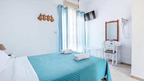 a bedroom with a blue bed with two towels on it at Melissani hotel in Sami