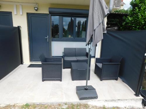 a patio with two chairs and an umbrella at Tsara Home in Le Trait