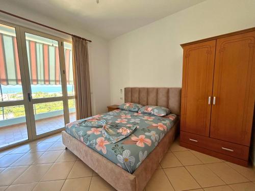 a bedroom with a bed and a cabinet and a window at Onis Sea View Apartments in Orikum