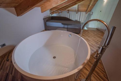 a white bath tub in a room with a bed at L'aja della Mirusina - Piedmont Resort Monferrato Langhe in Canelli