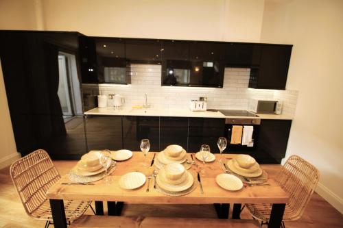a wooden table with hats and wine glasses in a kitchen at Sleeps 4 - Town Centre - Very High End Renovation - Private Garden - Close to Train Station - Fast Wifi in Berwick-Upon-Tweed
