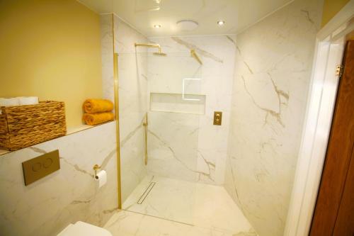 a bathroom with a shower with white marble walls at Sleeps 4 - Town Centre - Very High End Renovation - Private Garden - Close to Train Station - Fast Wifi in Berwick-Upon-Tweed