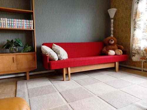 a red couch with a teddy bear sitting on it at Marjula in Kokkola