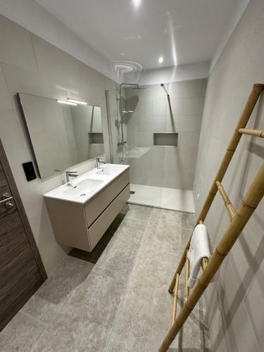 une salle de bain blanche avec un lavabo et un miroir dans l'établissement Résidence du Château d'eau, à Porticcio