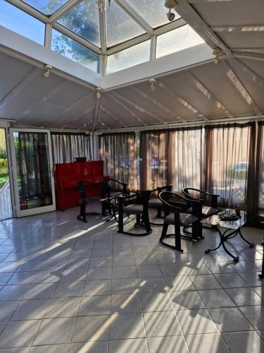 a conservatory with tables and chairs in a room with windows at Hotel Athina in Asprovalta