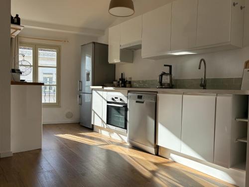 une cuisine avec des appareils blancs et un parquet dans l'établissement Appartement intra-muros Avignon, à Avignon