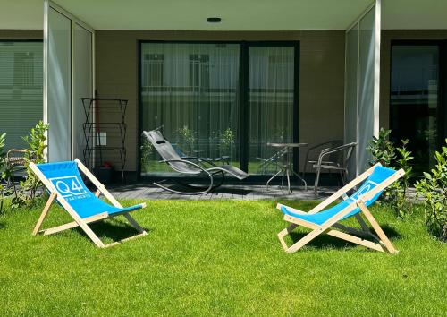 two chairs sitting in the grass in front of a house at Apartamenty Florina Q4Apartments in Łeba