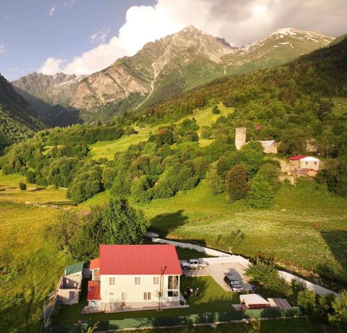 a house in a valley with mountains in the background at Guest House Gogia in Zhabeshi