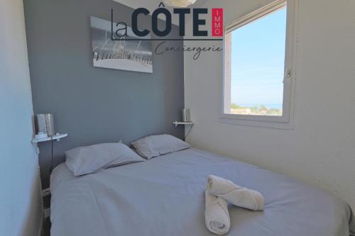 un lit blanc avec une paire de chaussures assise sur le lit dans l'établissement Les embruns, à Sausset-les-Pins