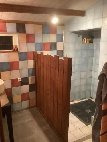 La salle de bains est pourvue d'une porte en bois. dans l'établissement Charmante maison atypique en village, à Saint-Colombin