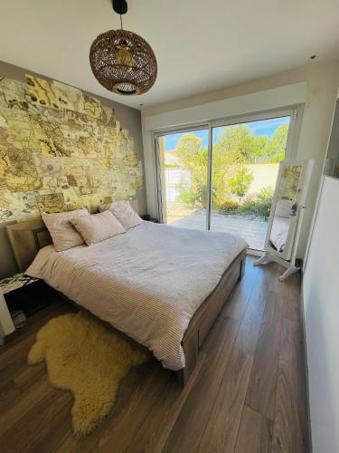 une chambre avec un grand lit avec un mur en pierre dans l'établissement Charmante villa avec piscine chauffée, proximité des plages, à Vias