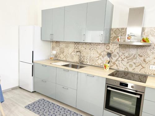 Casa Giannina a Marina di Cecina by Zoom In Earth في مارينا دي سيسينا: مطبخ أبيض مع دواليب بيضاء ومغسلة