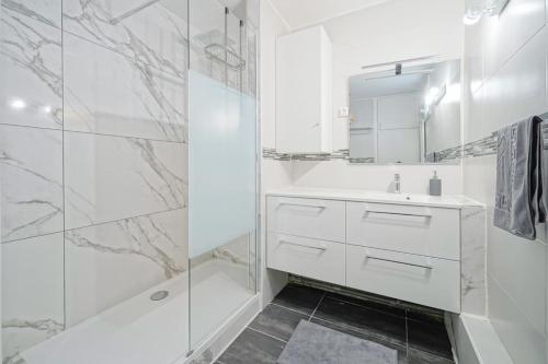 Un baño blanco con lavabo y ducha. en Doorman - Spacious 2BR Paris, en Saint-Ouen