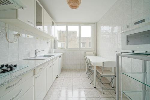 une cuisine blanche avec un évier et une table dans l'établissement Doorman - Spacious 2BR Paris, à Saint-Ouen