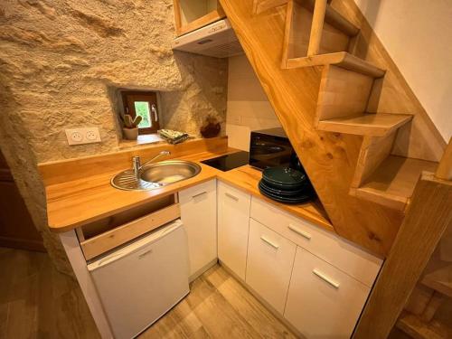Elle comprend une petite cuisine avec un évier et un mur en pierre. dans l'établissement Pradelles, à Castelnau-de-Lévis