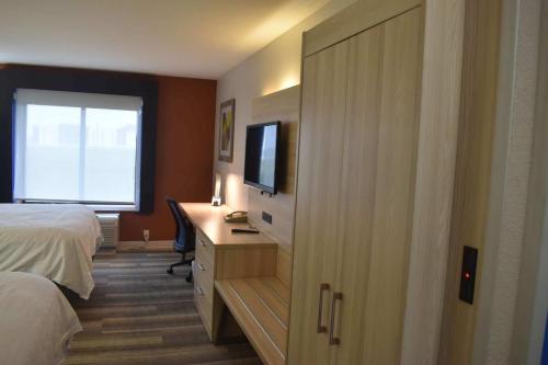 a bedroom with a bed and a desk with a television at Holiday Inn Express Hotel & Suites McPherson by IHG in McPherson