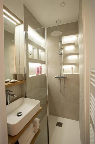 une salle de bain blanche avec un lavabo et une douche dans l'établissement Luxueux Appartement - Centre de Paris, à Paris