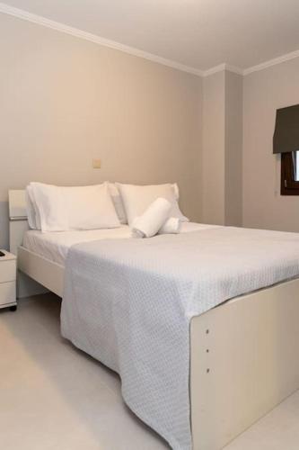 a white bedroom with a bed with white sheets and pillows at Το Σπίτι της Γιαγιάς 1 (Grandma's House 1) in Kondopoúlion