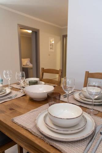 a wooden table with plates and bowls and wine glasses at Το Σπίτι της Γιαγιάς 1 (Grandma's House 1) in Kondopoúlion