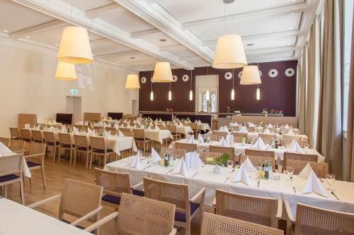 um salão de banquetes com mesas e cadeiras brancas em Kardinal Schulte Haus em Bergisch Gladbach
