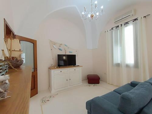 Una sala de estar con un sofá azul y un televisor. en Adelè posto tranquillo al centro del paese, en Santa Cesarea Terme
