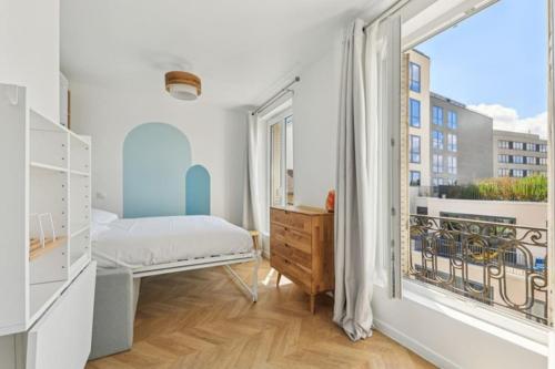 une chambre avec un lit et une grande fenêtre dans l'établissement Studio cosy aux portes de Paris, à Montrouge