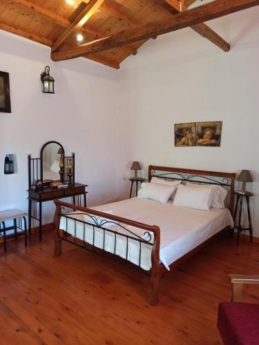 een slaapkamer met een groot bed en een houten vloer bij Casa de la Fuente in Ditropo