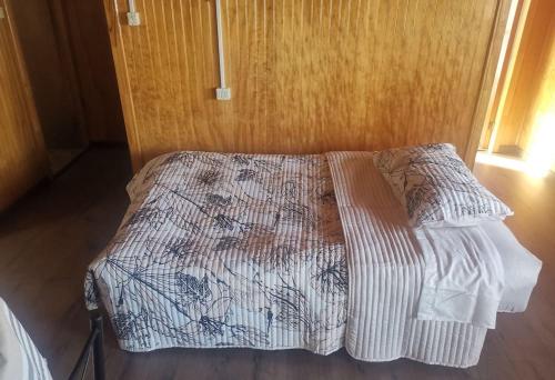 a bed in a bedroom with a wooden wall at Cabaña, excelente ubicación in Puerto Montt