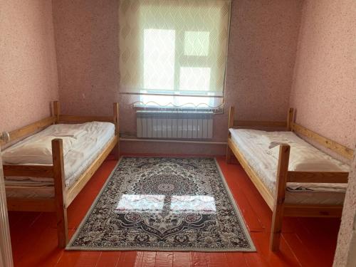 a room with two beds and a rug on the floor at Naryn Guest House in Naryn