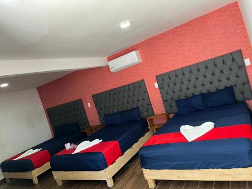 two beds in a room with red and blue at Hotel La Intimidad in Antón Lizardo