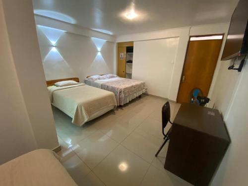 a room with two beds and a desk in it at Hotel Orozco in Antofagasta