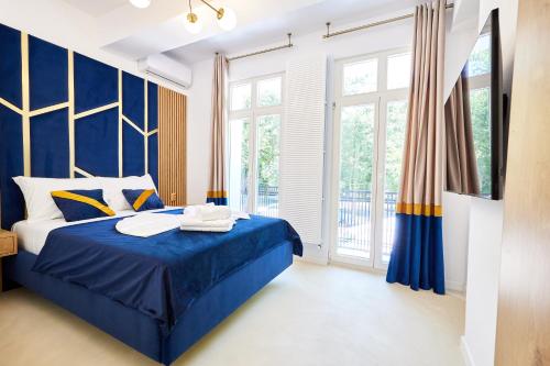 a blue and white bedroom with a bed and windows at Carol Park View in Bucharest