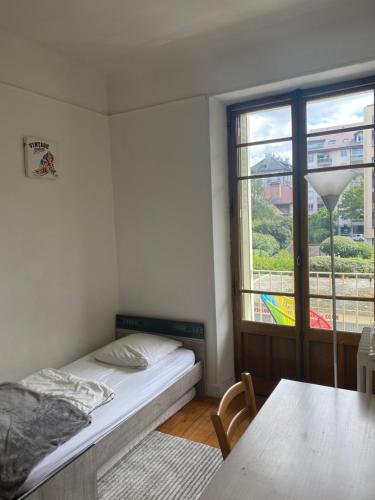 une chambre avec un lit, une table et une fenêtre dans l'établissement Appartement au coeur d'Annecy, à Annecy