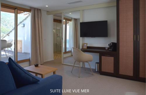 a living room with a couch and a desk with a tv at HOTEL SAINT ROCH in Ogliastro